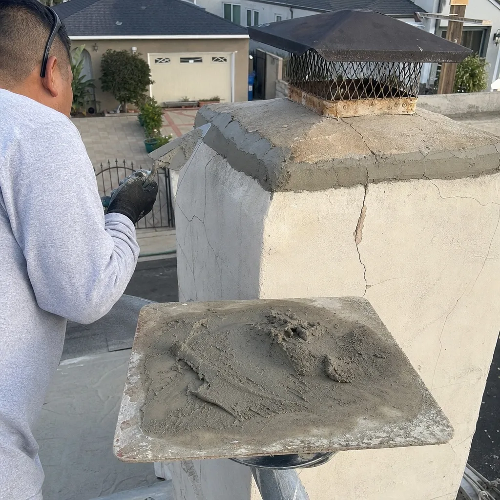 Professional mason performing chimney crown repair and crack sealing on a rooftop.